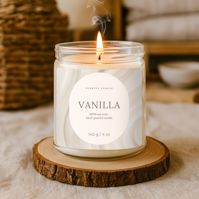 Op de afbeelding: Een brandende vanille geurkaars in een heldere glazen pot, op een houten onderzetter. Het etiket luidt "VANILLA" en "100% sojawas, handgegoten kaars". De kaars is 140 g.