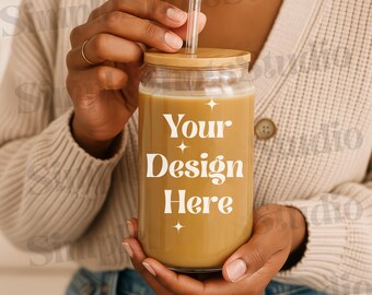 Op de afbeelding: Een persoon houdt een helder glazen glas met een bruine vloeistof en een bamboe deksel vast. Op het glas staat "Your Design Here".
