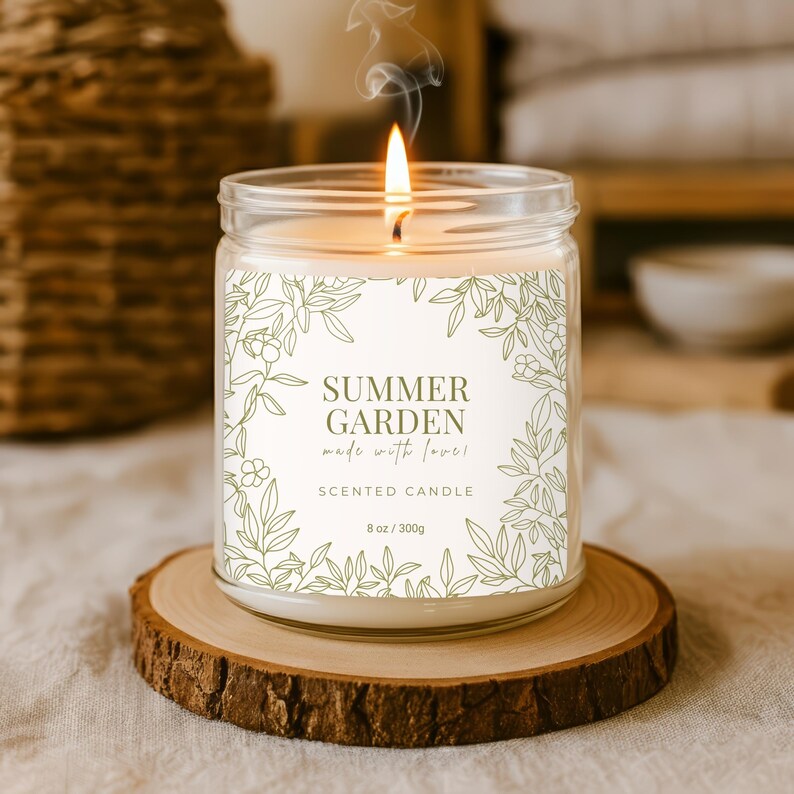 Op de afbeelding: Een brandende geurkaars in een glazen pot met een etiket met de tekst "Summer Garden made with love!" en "Scented Candle". De kaars staat op een houten onderzetter. De kaars is 300g.