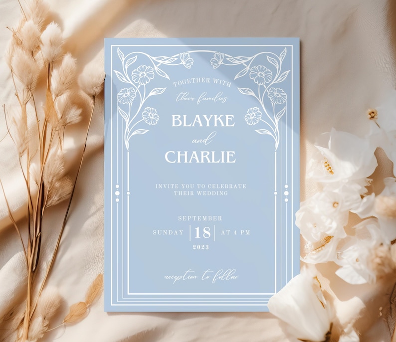May include: A light blue wedding invitation with white floral accents and text. The invitation reads "Together with their families, Blayke and Charlie invite you to celebrate their wedding, Sunday, September 18, 2023 at 4 PM. Reception to follow."