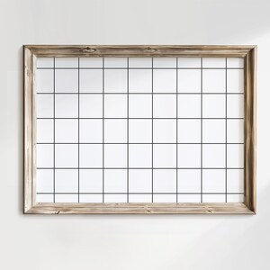 Op de afbeelding: Een houten frame met een wit rasterpatroon erin. Het frame is lichtbruin en heeft een rustieke uitstraling.
