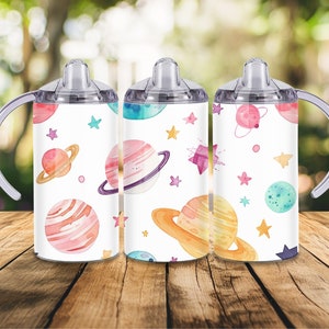 Peut inclure: Trois gobelets &agrave; bec blancs avec un th&egrave;me spatial &agrave; l'aquarelle color&eacute;e. Chaque gobelet pr&eacute;sente des plan&egrave;tes, des &eacute;toiles et d'autres corps c&eacute;lestes dans des tons de rose, orange, bleu et violet. Ils ont des poign&eacute;es et des couvercles transparents.