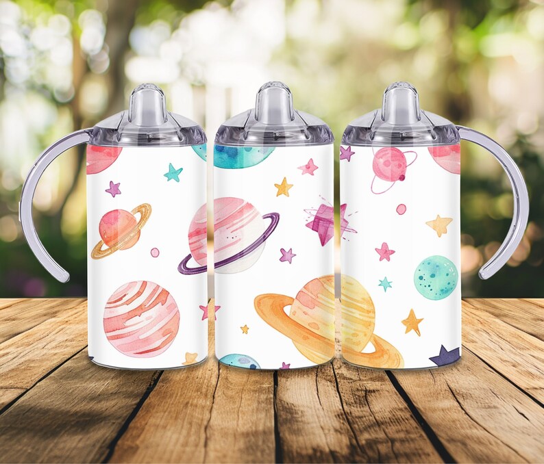 Peut inclure: Trois gobelets &agrave; bec blancs avec un th&egrave;me spatial &agrave; l'aquarelle color&eacute;e. Chaque gobelet pr&eacute;sente des plan&egrave;tes, des &eacute;toiles et d'autres corps c&eacute;lestes dans des tons de rose, orange, bleu et violet. Ils ont des poign&eacute;es et des couvercles transparents.