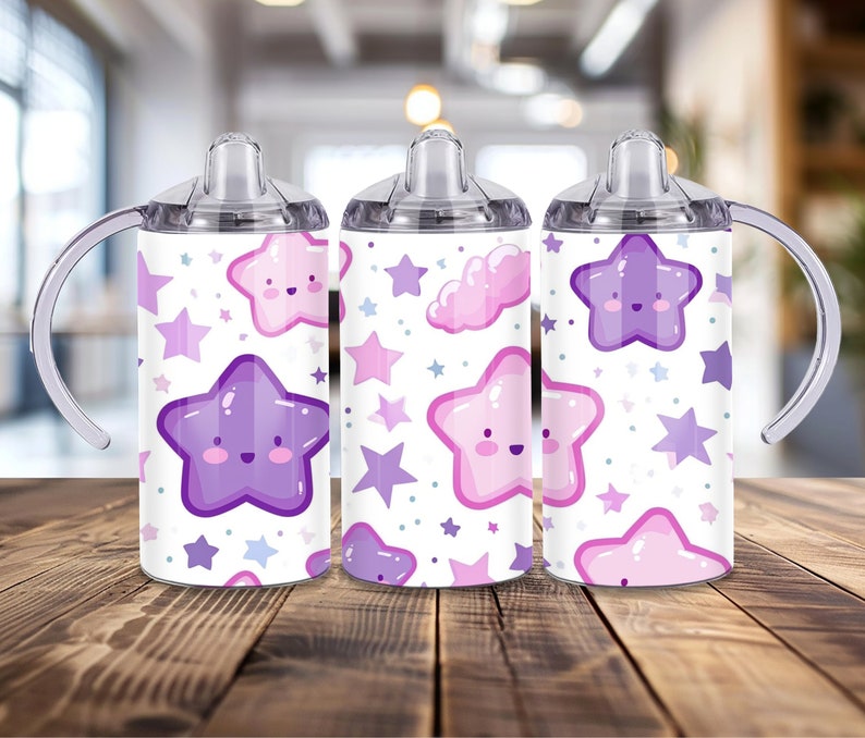 Peut inclure: Trois gobelets &agrave; bec blancs avec un motif d'&eacute;toiles. Le motif comprend des &eacute;toiles souriantes et des nuages dans des tons de violet et de rose. Chaque tasse a un couvercle transparent et une poign&eacute;e incurv&eacute;e.