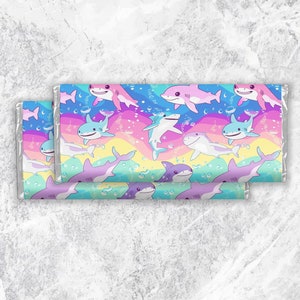 Pu&ograve; includere: Uno sfondo arcobaleno colorato con un motivo ripetuto di squali dei cartoni animati in vari colori, tra cui rosa, blu e viola. Gli squali nuotano in un motivo arcobaleno con bolle.