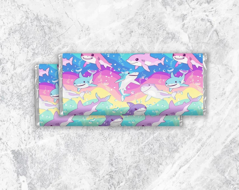 Pu&ograve; includere: Uno sfondo arcobaleno colorato con un motivo ripetuto di squali dei cartoni animati in vari colori, tra cui rosa, blu e viola. Gli squali nuotano in un motivo arcobaleno con bolle.