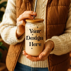 May include: A person holding a clear glass with a bamboo lid and a straw. The glass is filled with a light brown liquid and has the text "Your Design Here" printed on it.