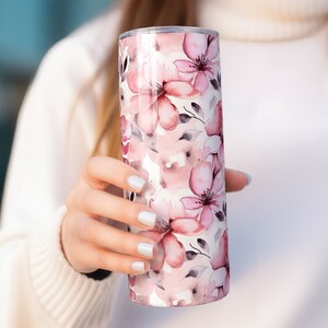 May include: A stainless steel tumbler with a pink and white floral pattern. The tumbler has a lid and is perfect for keeping drinks hot or cold.
