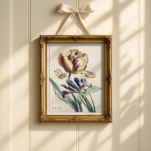 Op de afbeelding: Een ingelijste botanische prent met een gedetailleerde illustratie van een tulp, iris en vlinder. Het kunstwerk zit in een gouden, sierlijke lijst, opgehangen aan een cr&egrave;mekleurig lint. De bloemen zijn in tinten paars, geel en blauw.