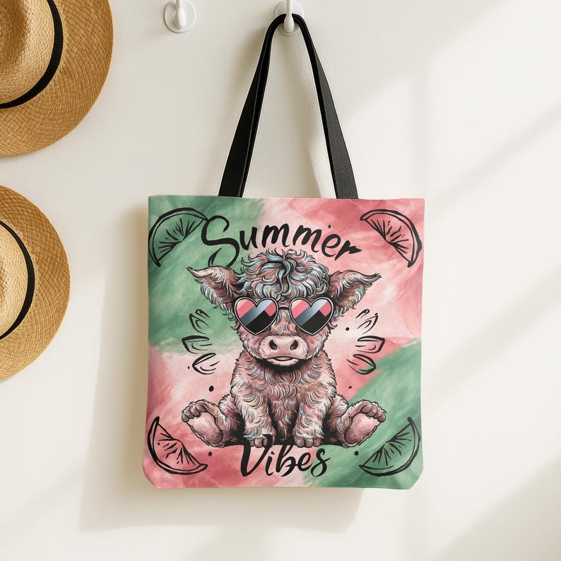May include: A pink and green tote bag with a cartoon highland cow wearing sunglasses. The bag has the text "Summer Vibes" printed on it.