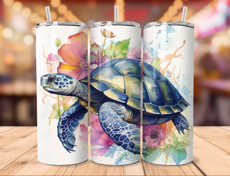 Puede incluir: Tres vasos de acero inoxidable con fondo blanco y un dise&ntilde;o de acuarela de una tortuga marina nadando a trav&eacute;s de un campo de flores rosas, moradas y azules.
