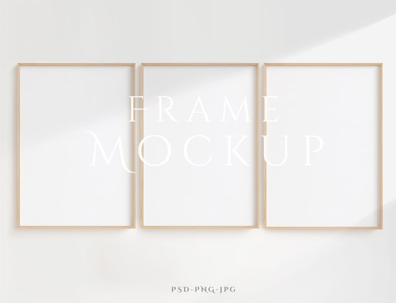 Peut inclure: Trois cadres photo en bois avec des passe-partout blancs, dispos&eacute;s horizontalement sur un mur blanc. Les cadres sont vides et pr&ecirc;ts &agrave; accueillir vos photos ou vos &oelig;uvres d'art.  FRAME MOCKUP est &eacute;crit en blanc sur le cadre du milieu.