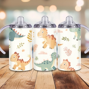 Peut inclure: Trois gobelets &agrave; bec blancs avec des poign&eacute;es et des couvercles transparents. Chaque gobelet pr&eacute;sente un motif r&eacute;p&eacute;t&eacute; de dinosaures de dessins anim&eacute;s dans des tons de vert, d'orange et de jaune, ainsi que des nuages roses et des feuilles marron. Les gobelets sont con&ccedil;us pour les enfants.