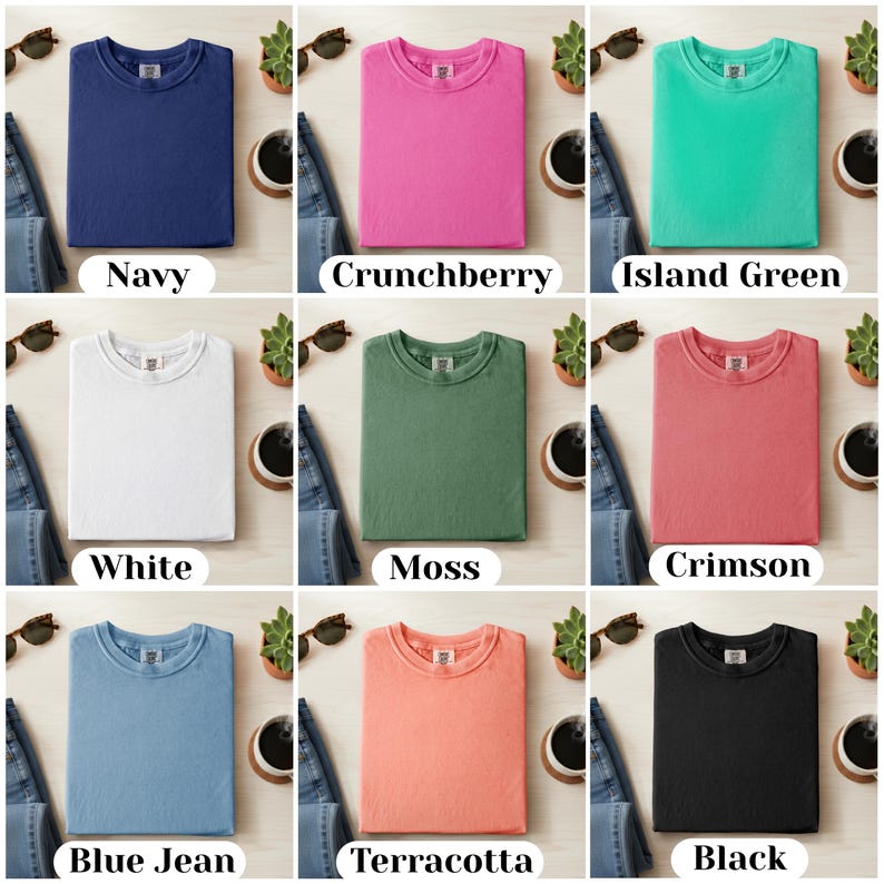 May include: Nine different solid-color t-shirts are displayed, including navy, crunchberry, island green, white, moss, crimson, blue jean, terracotta, and black. Each shirt is folded and presented with a label indicating its color.