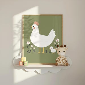 K&ouml;nnte beinhalten: Ein gerahmter Druck mit einer wei&szlig;en Henne und einem K&uuml;ken auf gr&uuml;nem Hintergrund mit wei&szlig;en Blumen. Das Kunstwerk hat einen hellen Holzrahmen und wird &uuml;ber einem wolkenf&ouml;rmigen Regal mit einem Giraffen-Pl&uuml;schtier und ABC-Bl&ouml;cken ausgestellt.