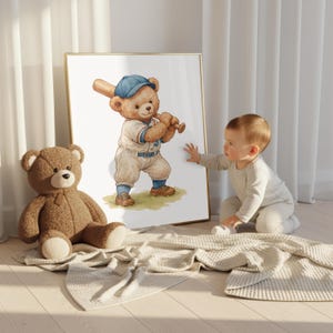 K&ouml;nnte beinhalten: Ein gerahmter Druck mit einer Aquarellillustration eines Teddyb&auml;ren in Baseballuniform, der einen Schl&auml;ger h&auml;lt. Ein Pl&uuml;schteddyb&auml;r und ein Baby sind ebenfalls im Bild. Der Druck hat einen goldenen Rahmen.