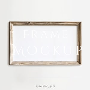 May include: A light brown wood frame with a white mat and the text "FRAME MOCKUP" printed in white on the mat.