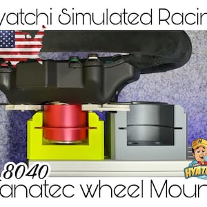 Puede incluir: Un volante de carreras negro con botones y un soporte de volante Fanatec gris y amarillo. El soporte está etiquetado como "8040 Fanatec wheel Mount".