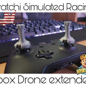 Könnte beinhalten: Ein schwarzer Xbox-Controller mit zwei grauen Drohnenverlängerungen, die an den Joysticks befestigt sind. Der Text "Hyatchi Simulated Racing" befindet sich oben im Bild. Der Text "Xbox Drone extenders" befindet sich unten im Bild.