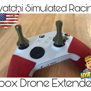 Könnte beinhalten: Ein weißer Xbox-Controller mit zwei grünen Drohnenverlängerungen, die an den Thumbsticks befestigt sind. Der Controller hat einen roten und weißen Griff. Der Text "Hyatchi Simulated Racing" befindet sich oben im Bild und "Xbox Drone Extenders" unten im Bild.
