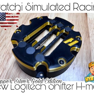 Könnte beinhalten: Ein schwarzer und goldener Shifter mit einem Etikett in Kupfer-, Silber- und Goldausführung. Der Shifter ist für Logitech konzipiert und hat ein Hyatchi-Logo an der Seite. Der Shifter befindet sich auf einer Holzoberfläche.