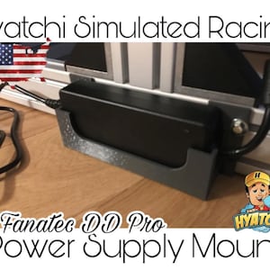 May include: A black Fanatec DD Pro power supply mount. The mount is holding a black power supply. The image includes the text "Hyatchi Simulated Racing" and "Fanatec DD Pro Power Supply Mount". An American flag graphic is in the upper left corner.