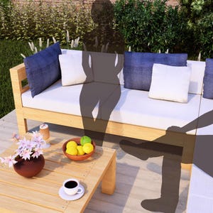 May include: A wooden outdoor couch with white cushions and blue throw pillows. A small wooden table with a bowl of lemons and a cup of coffee sits in front of the couch.