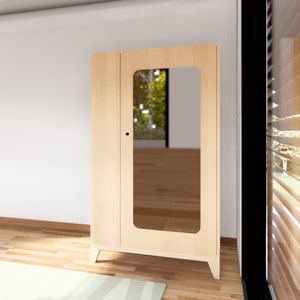 May include: A light wood cabinet with a single door and a mirror inset. The cabinet has a simple design with rounded edges and sits on four legs.