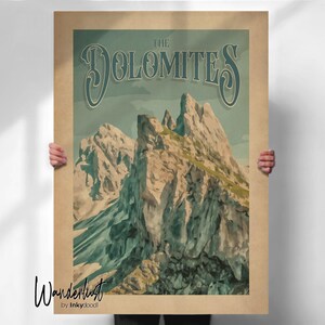 May include: A vintage-style poster featuring a mountain range with the text "The Dolomites" in a stylized font. The poster has a tan background with a light blue sky and mountain peaks. The word "Wanderlust" is written in cursive at the bottom.