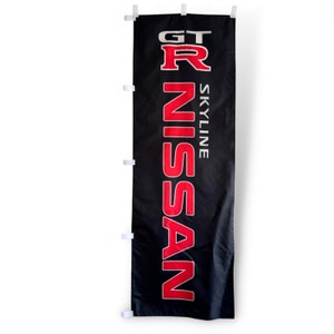 May include: Black banner with the text "GT R SKYLINE NISSAN" in red and white. The banner is rectangular and hangs vertically. White clips are attached along the left side of the banner.