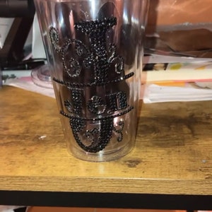 May include: A clear plastic tumbler with a black rhinestone design that spells out the word "Jen".