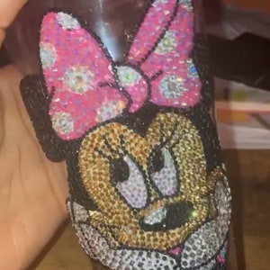 May include: A clear glass tumbler with a pink and black Minnie Mouse design covered in rhinestones.