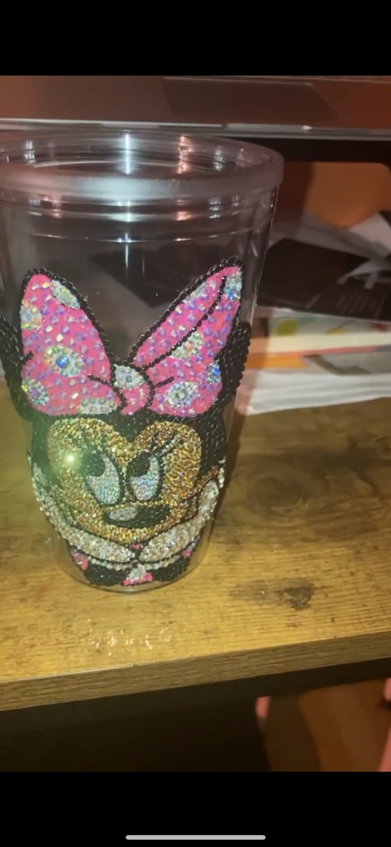 May include: A clear plastic tumbler with a rhinestone design of Minnie Mouse. The design features a pink bow, black ears, and a gold face.
