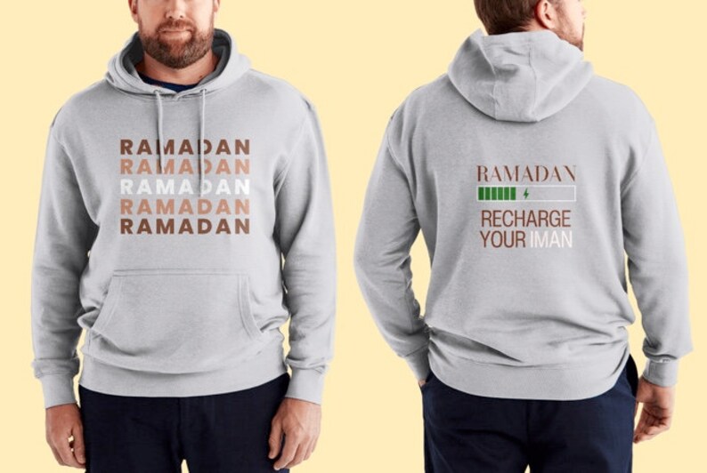 Puede incluir: Una sudadera gris con la palabra "RAMADAN" repetida cinco veces en diferentes tonos de marr&oacute;n en la parte delantera. La parte posterior de la sudadera tiene la palabra "RAMADAN" con una barra de bater&iacute;a verde y el texto "RECHARGE YOUR IMAN".