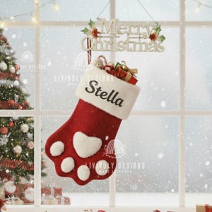 May include: A festive red Christmas stocking in the shape of a paw, featuring white detailing and the name "Stella". It's filled with presents and hangs beneath a "Merry Christmas" sign. A Christmas tree and falling snow are seen in the background.