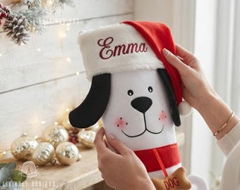 May include: A white plush dog Christmas stocking featuring black ears, a red collar with a brown bone-shaped tag labeled DOG, and a red Santa hat cuff embroidered with the name Emma in dark red script lettering.