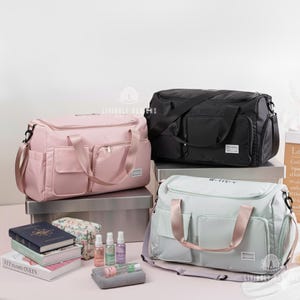 K&ouml;nnte beinhalten: Drei gro&szlig;e, rechteckige Reisetaschen in Rosa, Schwarz und Hellgr&uuml;n. Jede Tasche hat mehrere Au&szlig;entaschen, einen Schultergurt und einen oberen Griff. Die Taschen werden auf einer wei&szlig;en Oberfl&auml;che mit Zubeh&ouml;r pr&auml;sentiert.
