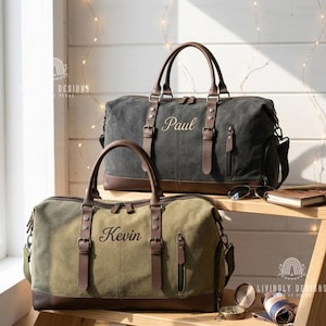 May include: Two canvas duffel bags with brown leather accents and handles. The top bag is charcoal gray with the name Paul embroidered in script. The bottom bag is olive green with the name Kevin embroidered in script. Both feature side pockets.