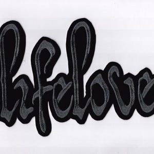 May include: Black and gray embroidered patch with the word "lifelover" in a stylized script font. The patch has a black background with gray stitching, and is set against a white background.