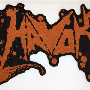 May include: Embroidered patch featuring the word "HAVAK" in orange, stylized with a dripping effect, set against a black, irregular background. The patch has a distressed, grunge aesthetic.
