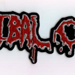 May include: A rectangular embroidered patch featuring the text CANNIBAL CORPSE in a stylized, dripping red font with a white outline and a thick black border. The lettering has a textured appearance, mimicking a bleeding or liquid effect.
