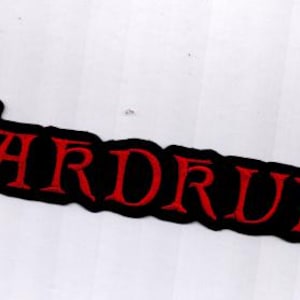 May include: Embroidered patch with the word "WARDRUNA" in red capital letters. The text is outlined in black and has a stylized, gothic font. The patch is rectangular and has a black border.