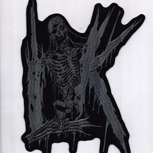 Könnte beinhalten: Ein schwarzer und grauer Aufnäher mit einer skelettartigen Figur mit detailliertem Brustkorb und Schädel. Das Design hat eine dunkle, gotische Ästhetik mit tropfenden Akzenten und einer stilisierten Form. Der Aufnäher ist wahrscheinlich für Kleidung oder Accessoires.