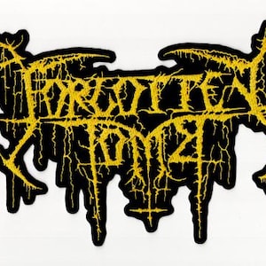 May include: Black patch with the text "FORGOTTEN TOMB" in yellow, stylized lettering. The patch has a unique, dripping design, with yellow accents outlining the black shape. The patch is likely for clothing or accessories.