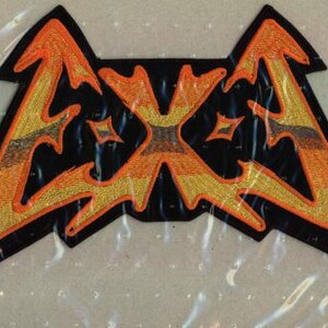 May include: Embroidered patch featuring a stylized orange and yellow lightning bolt design on a black background. The patch has a unique shape with pointed edges and decorative elements. The design includes star-shaped accents.