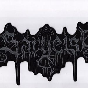 Può includere: Toppa nera con la scritta "Enthralled" in un font gotico, con accenti gocciolanti e pentagrammi. La toppa è su sfondo bianco. La toppa è probabilmente per una band o relativa alla musica heavy metal.