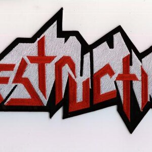 Può includere: Toppa ricamata con la scritta "DESTRUCTION" in lettere rosse, in grassetto e stilizzate con un contorno nero, su sfondo bianco. La toppa ha un design frastagliato e angolare, adatta per abbigliamento o accessori.