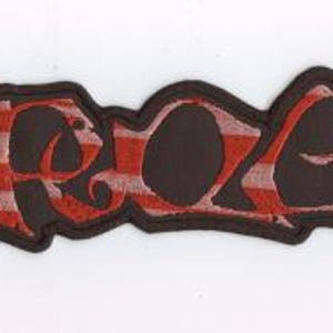 May include: A rectangular patch with the word "ASREOG" in a stylized font. The letters are a dark brown color with a red and white plaid pattern inside. The patch has a dark brown border.