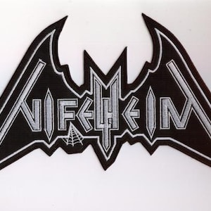 Könnte beinhalten: Schwarz-weißer, gestickter Aufnäher mit dem Wort "NIFELHEIM" in stilisierten Buchstaben. Der Aufnäher hat eine fledermausartige Form mit spitzen Kanten und einem Spinnennetz-Motiv.
