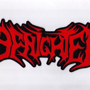 May include: A red and black patch with the word "BESIEGED" in a stylized, gothic font. The text is in red with a black outline, set against a white background. The design has a jagged, aggressive aesthetic.